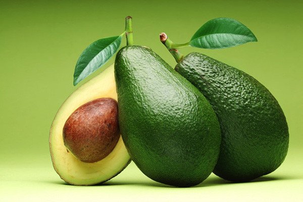 Những quả bơ xanh tươi đặt ngoài tủ lạnh, minh họa cách ủ chín tự nhiên trước khi đưa vào bảo quản lạnh.